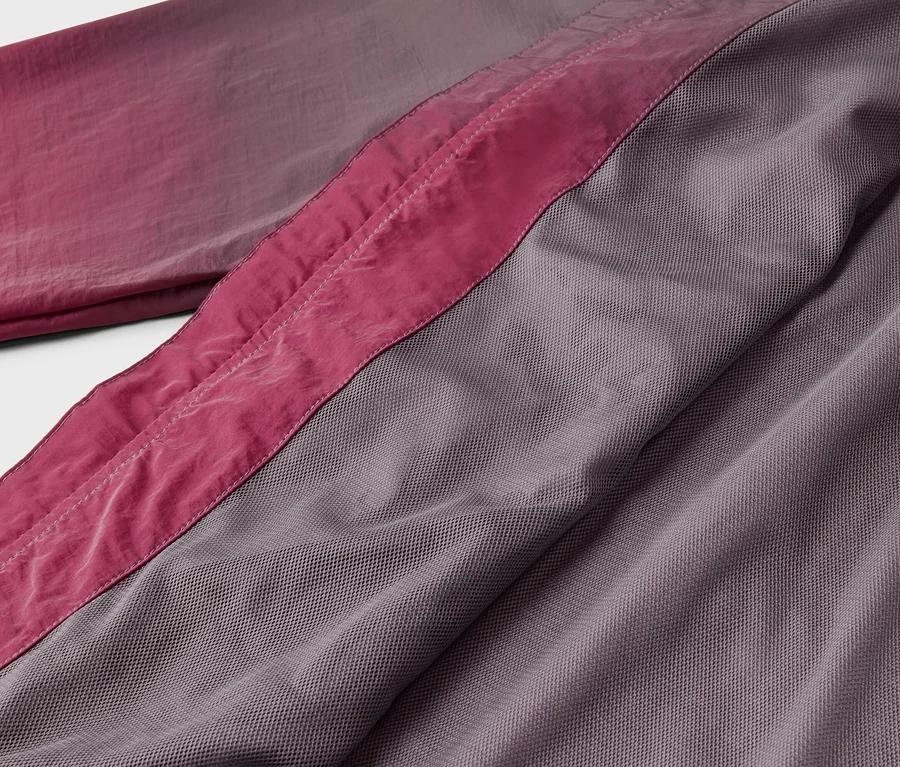 Gros plan d'un tissu dans les tons rose et gris avec une couture rose.