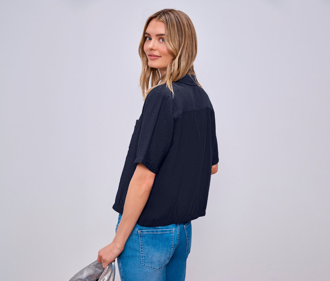 Femme regardant par-dessus son épaule portant un chemisier Street One et un jean.