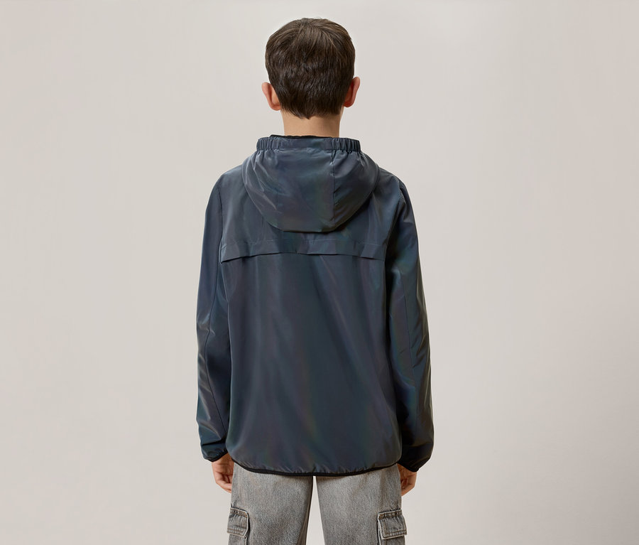 Vue arrière d'un garçon aux cheveux bruns portant une veste à capuche bleu foncé chatoyante et un pantalon cargo gris.