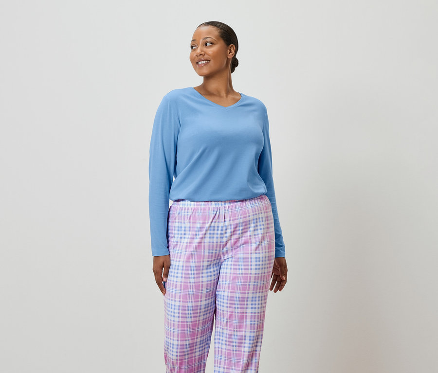 Femme portant un pull bleu clair et un pantalon de pyjama à carreaux.