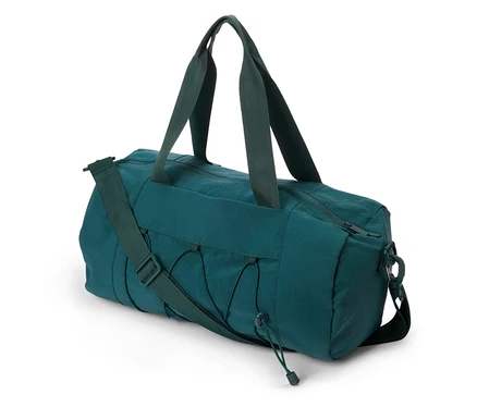 Sac de sport vert avec poignées et bandoulière posé sur le sol.