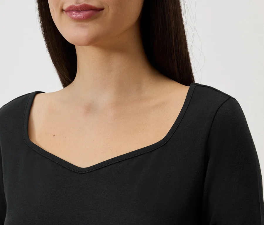 Gros plan d'une femme aux longs cheveux foncés portant un haut noir à manches longues et encolure en V.