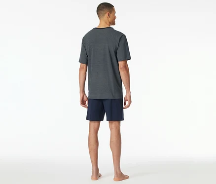 Homme vu de dos portant un ensemble de pyjama court SCHIESSER avec un haut à motif bleu et un short bleu marine.