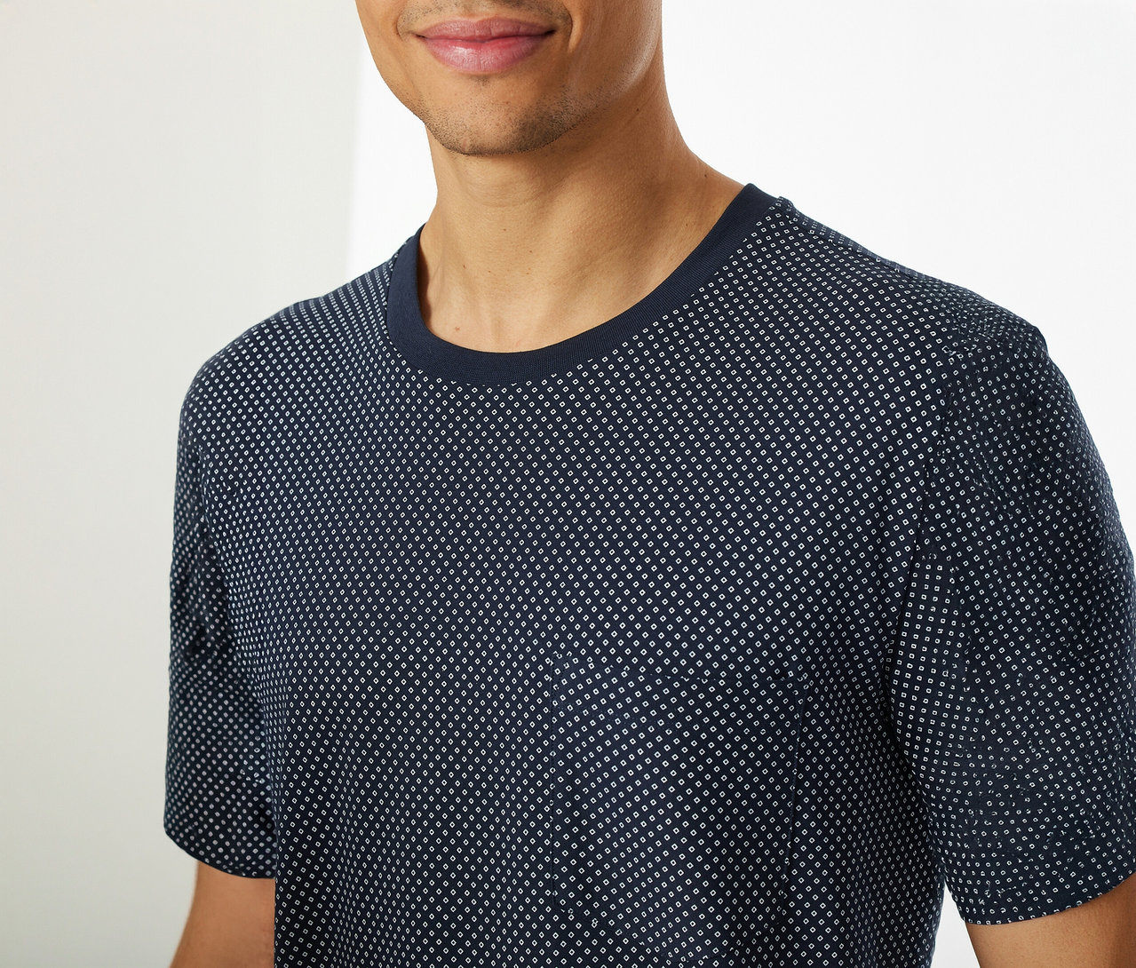 Un homme porte un lot de pyjama court SCHIESSER composé d’un haut bleu à manches courtes avec un motif à pois.