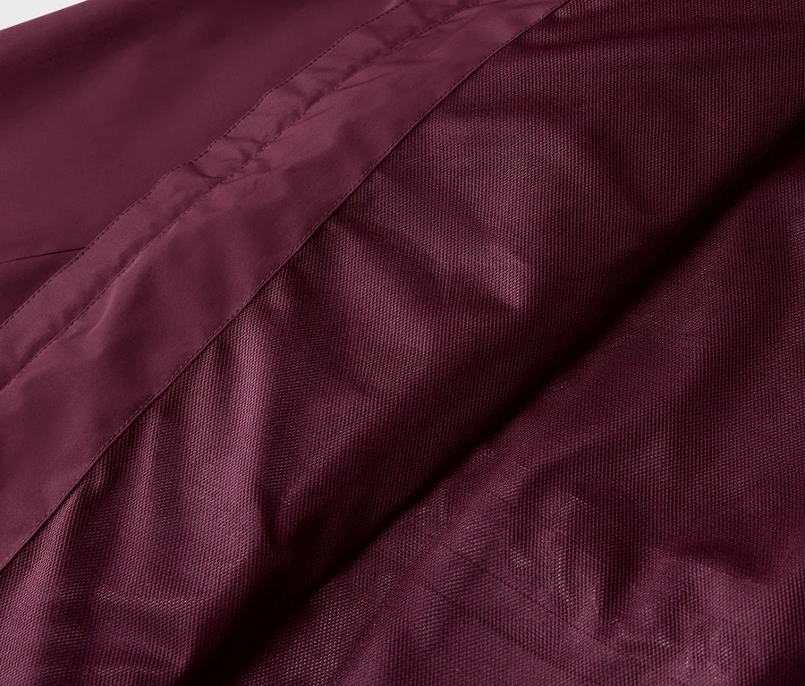 Gros plan d'un tissu bordeaux avec une texture lisse et en maille, relié par une couture.