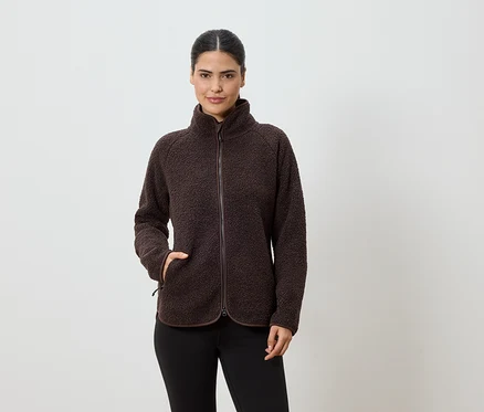 Une femme aux cheveux attachés en queue de cheval porte une veste polaire marron zippée et un legging noir sur fond blanc.
