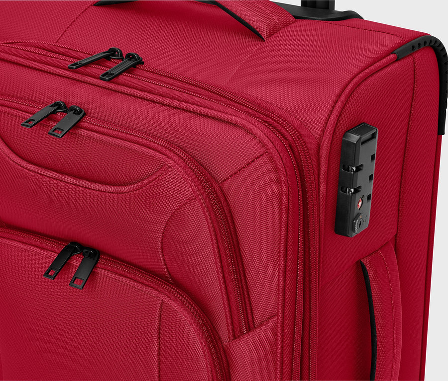 Gros plan d'une valise rouge en tissu avec des fermetures éclair noires et un cadenas à combinaison.