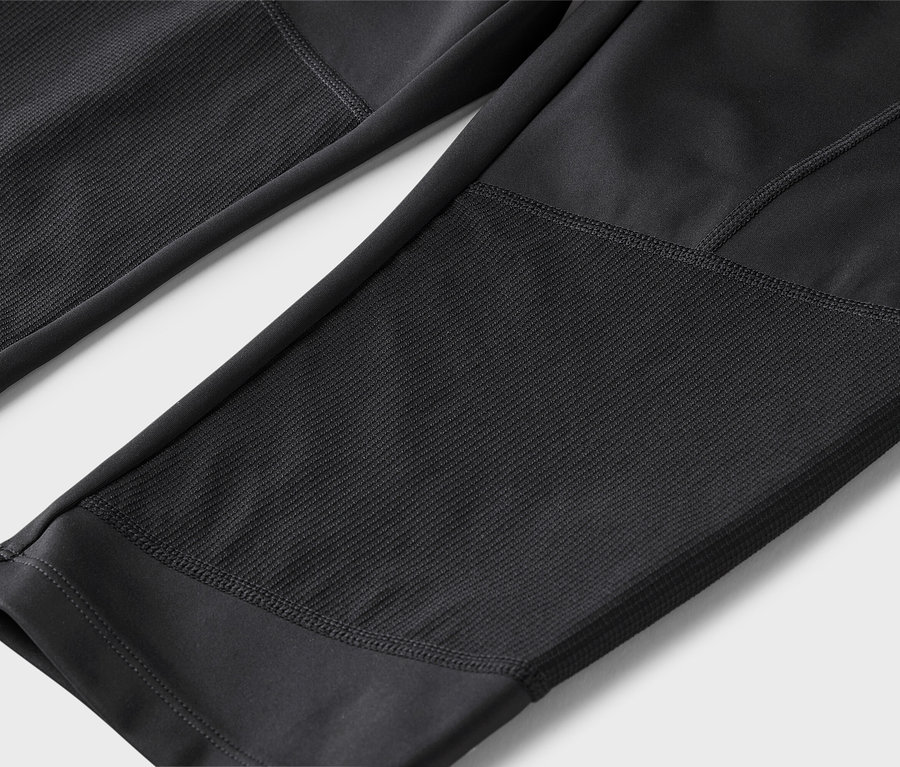 Gros plan d'un legging noir avec des empiècements texturés.
