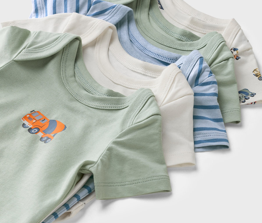 Gros plan de bodies pour bébé à manches courtes de différentes couleurs et motifs, dont un body vert avec un motif de bétonnière.