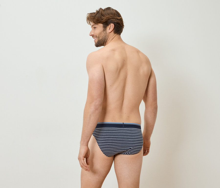 Homme de dos portant un slip rayé regardant par-dessus son épaule.