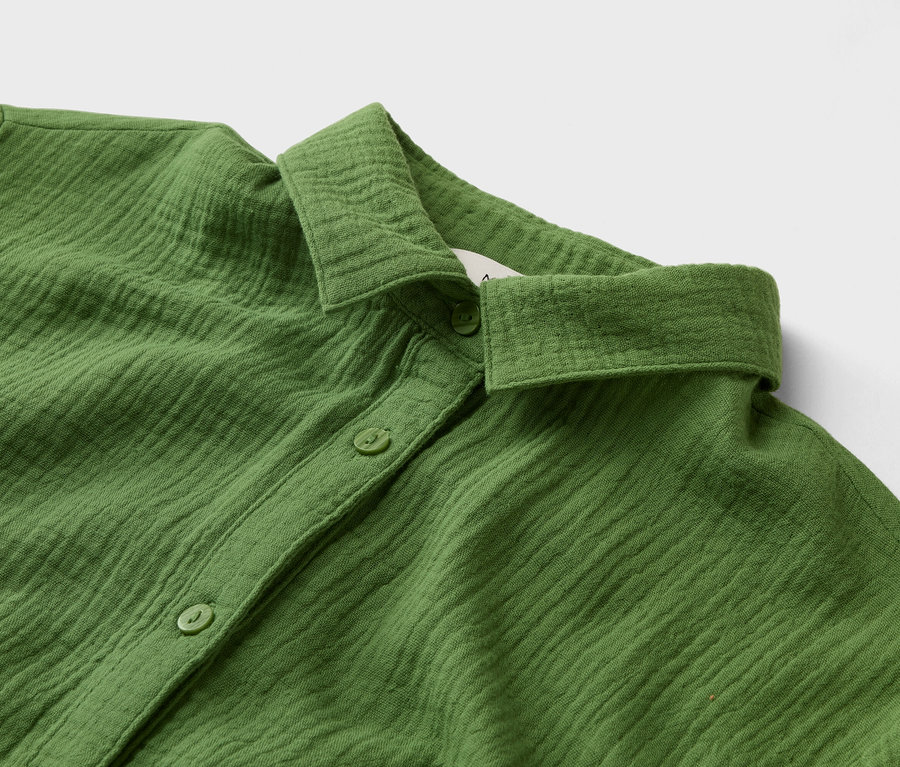 Gros plan d'une chemise verte avec un col et des boutons.