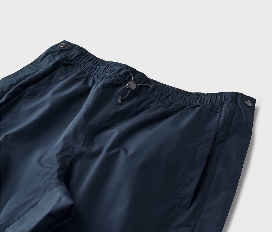 Gros plan d'un pantalon bleu marine avec taille élastique, cordon de serrage et poche latérale sur fond neutre.