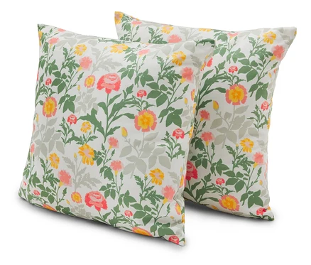 Deux coussins carrés à motifs floraux dans les tons de jaune, rose et vert sont posés sur un fond blanc.