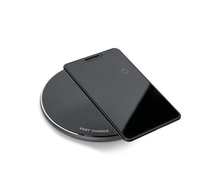 Un smartphone noir est posé sur un chargeur sans fil noir et rond.