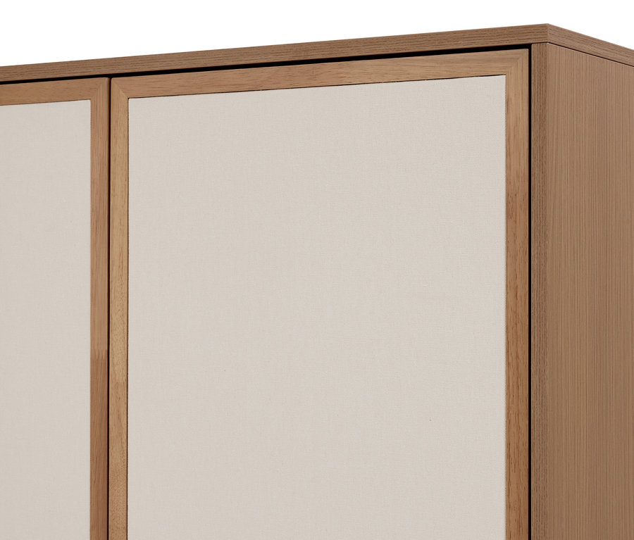 Gros plan d'une armoire en bois clair avec deux panneaux en tissu beige clair. Le côté droit montre le panneau latéral en bois de l'armoire.