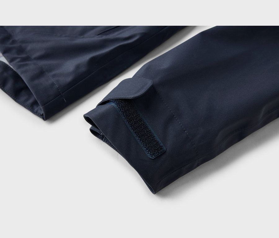 Gros plan d'une manche de veste bleu marine avec une fermeture auto-agrippante réglable au poignet.