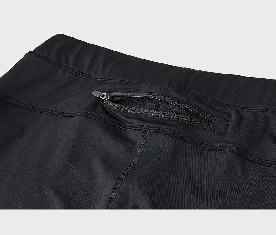 Gros plan d'un vêtement de sport noir montrant une poche zippée à l'arrière avec une doublure en maille visible à travers la fermeture éclair partiellement ouverte.