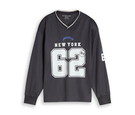 T-shirt gris foncé à manches longues avec un col en V et un liseré blanc. Sur la poitrine, on lit "NEW YORK" en blanc et en dessous le grand chiffre "62". Au-dessus de "NEW YORK", "Brooklyn" est écrit en bleu, et à côté du "2" se trouve un petit logo "NY".