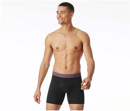 Homme souriant portant un boxer long SCHIESSER noir avec une ceinture violette.