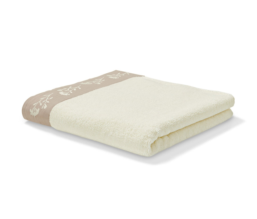 Drap de bain premium beige plié sur un fond blanc.