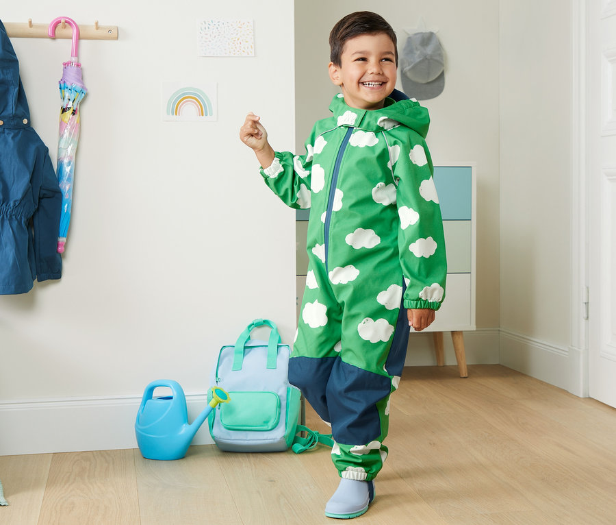 Garçon portant une combinaison softshell en matériaux recyclés verte à motifs de nuages.