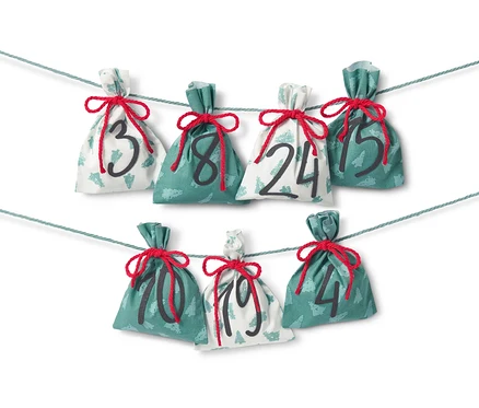 Kit de couture « Calendrier de l’Avent en tissu » avec sept sacs en tissu numérotés 3, 8, 24, 15, 10, 19 et 4, suspendus à une ficelle.