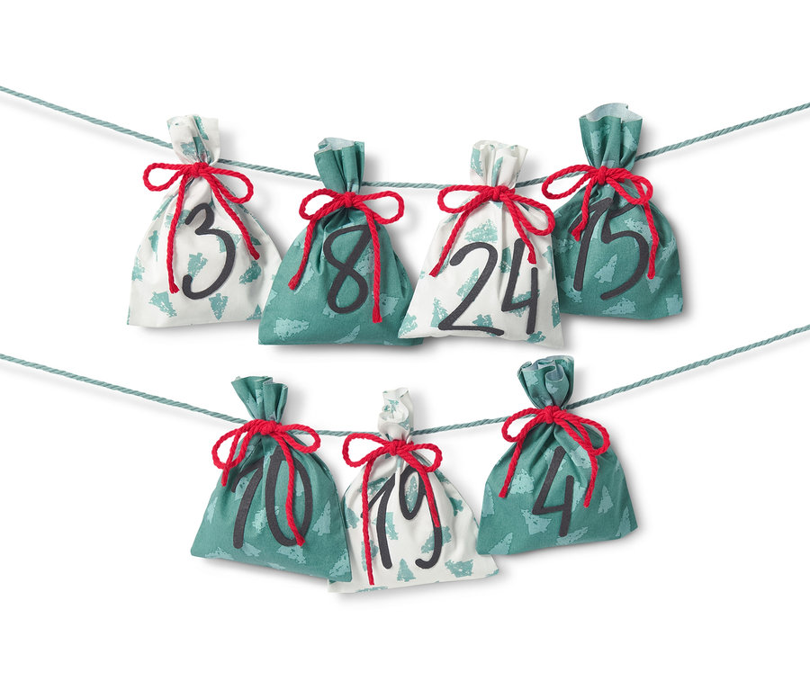 Kit de couture « Calendrier de l’Avent en tissu » avec sept sacs en tissu numérotés 3, 8, 24, 15, 10, 19 et 4, suspendus à une ficelle.
