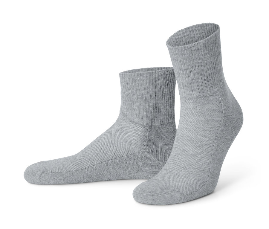 Deux paires de chaussettes fonctionnelles unisexes grises sont posées sur le sol.