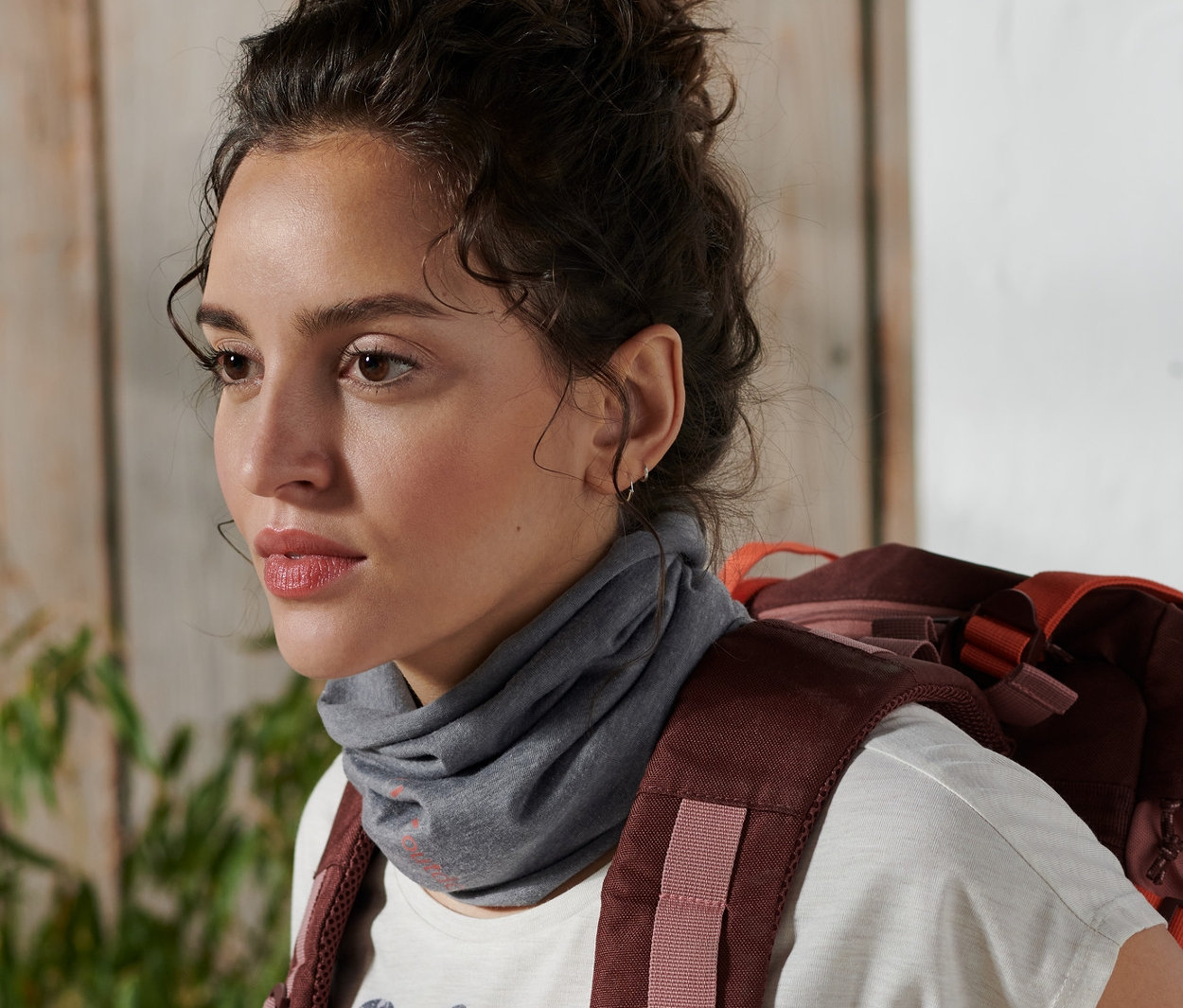 Une femme avec un sac à dos porte un foulard multifonction autour du cou.