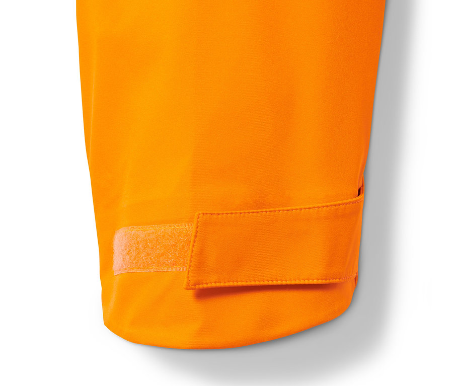 Détail d'une veste de ski hardshell orange avec fermeture velcro.