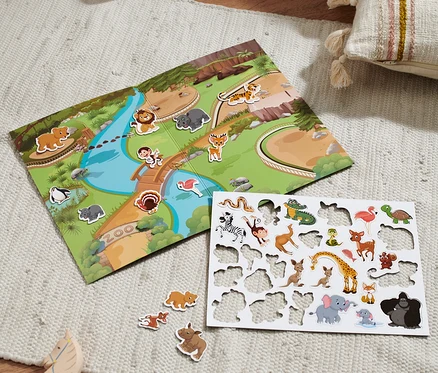 Un jeu sur le thème du zoo et une planche d'autocollants d'animaux sont disposés sur un tapis.