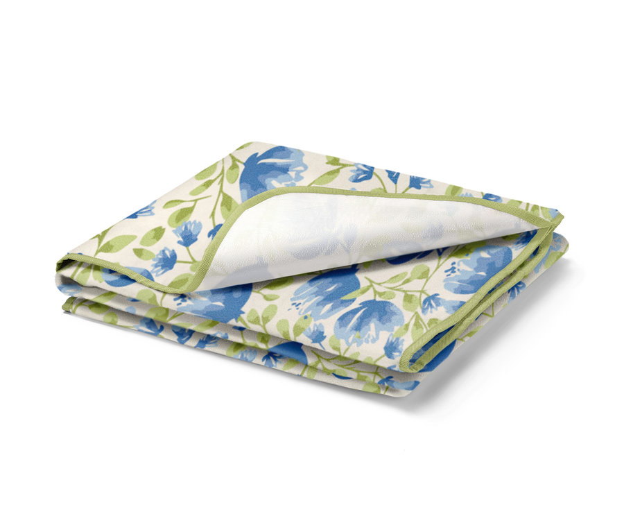 Petite nappe de pique-nique pliée avec motif floral bleu et bordure verte.