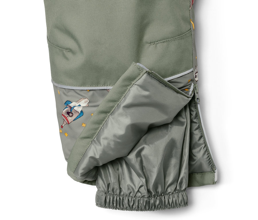 Détail de vêtements de neige pour enfant avec motif spatial et fermeture éclair ouverte.