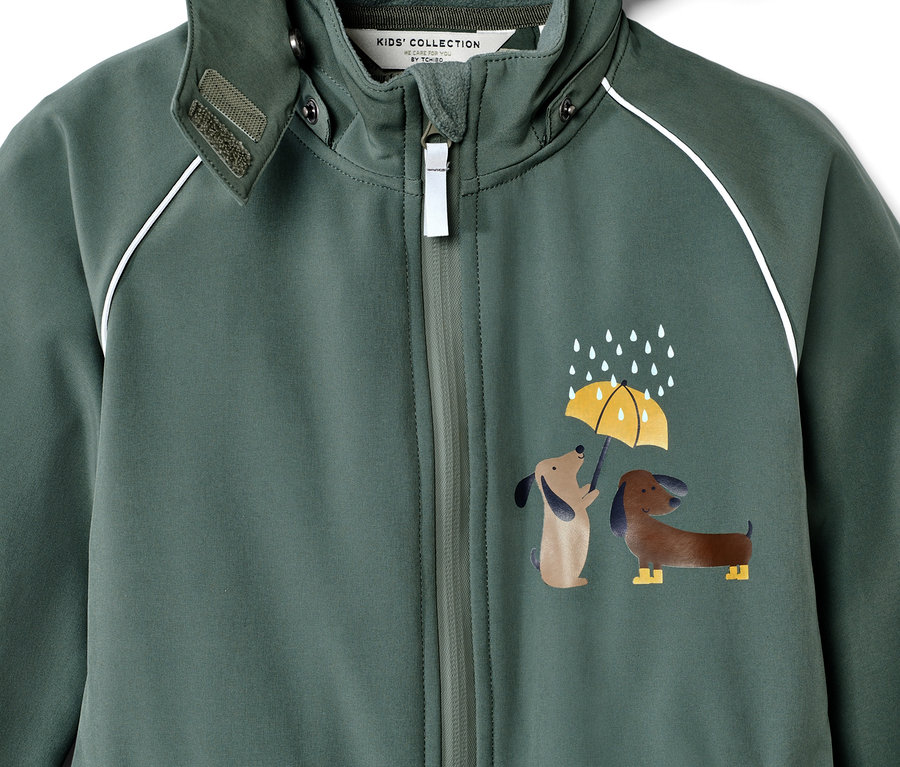 Gros plan sur une combinaison en softshell pour enfant avec un motif de chiens et de pluie.