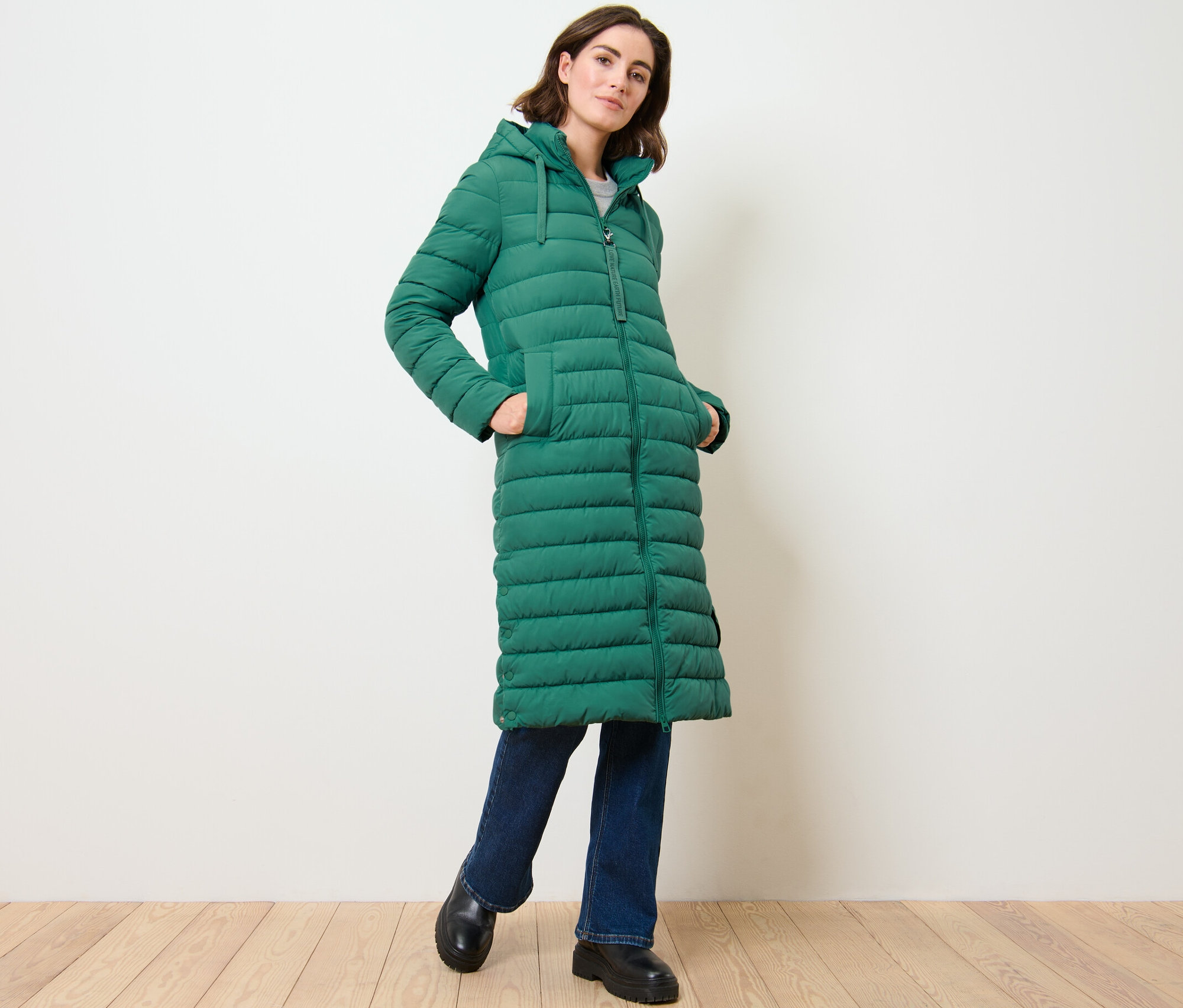 Femme posant dans un long manteau matelassé à capuche.