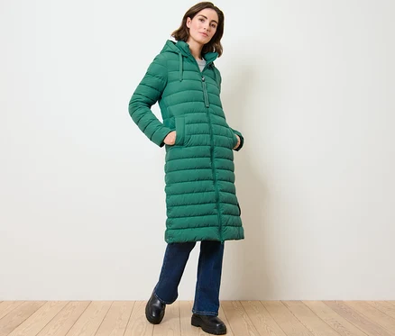 Femme posant dans un long manteau matelassé à capuche.