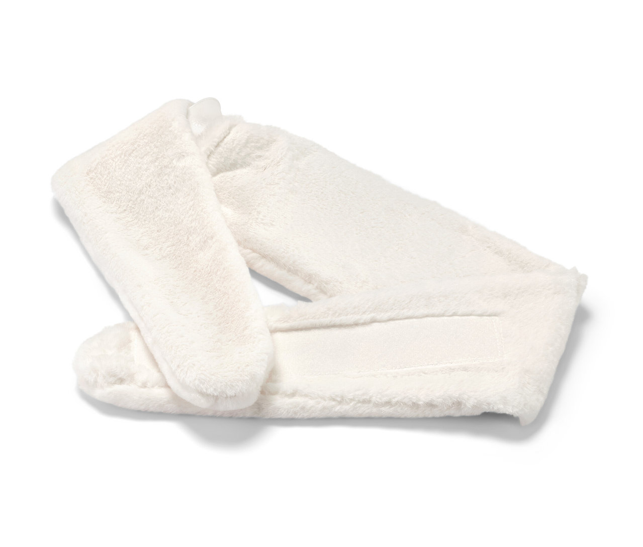 Une bouillotte blanche en peluche avec un ruban repose sur un fond blanc.