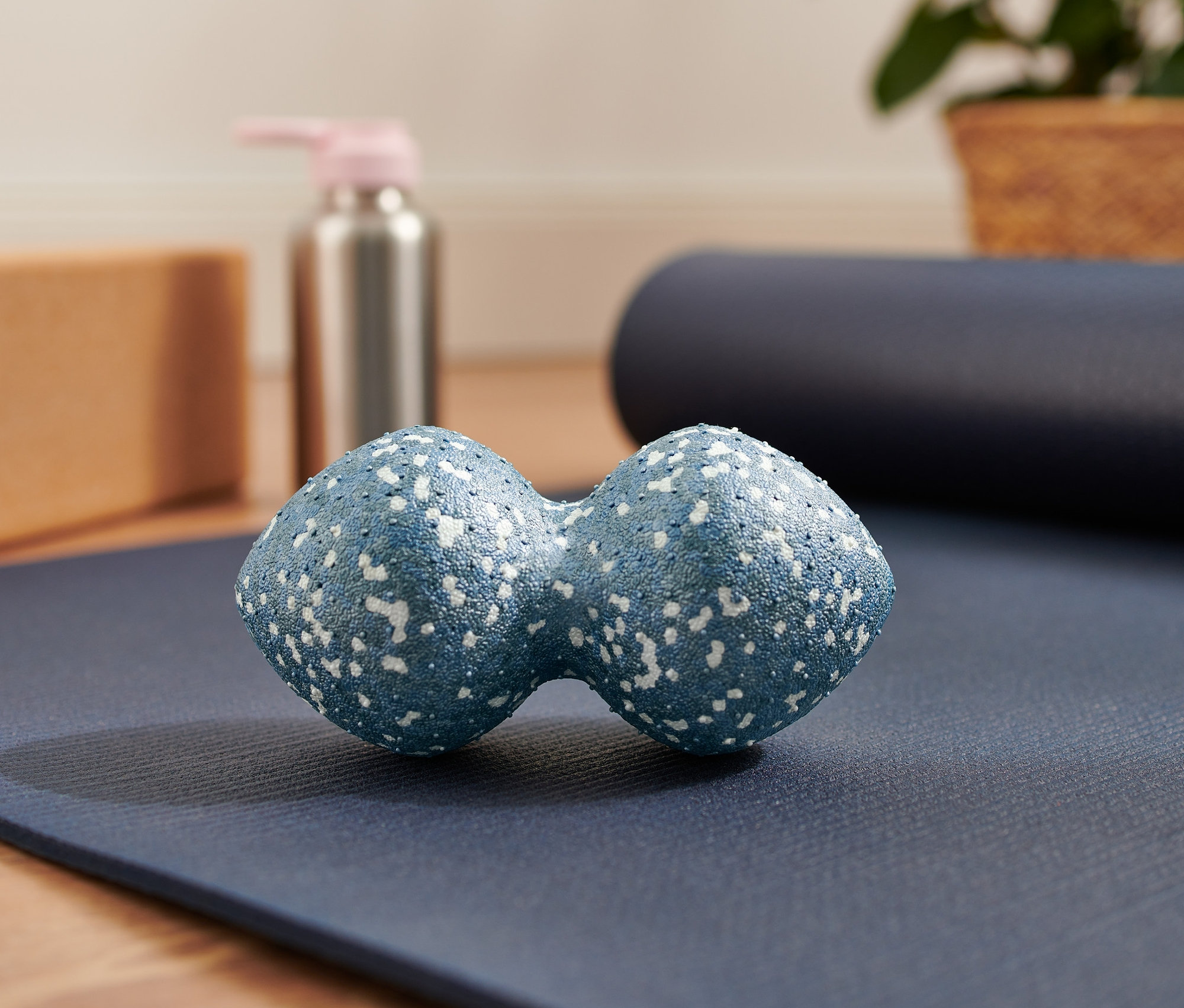 Une double balle de massage bleue posée sur un tapis de yoga bleu.