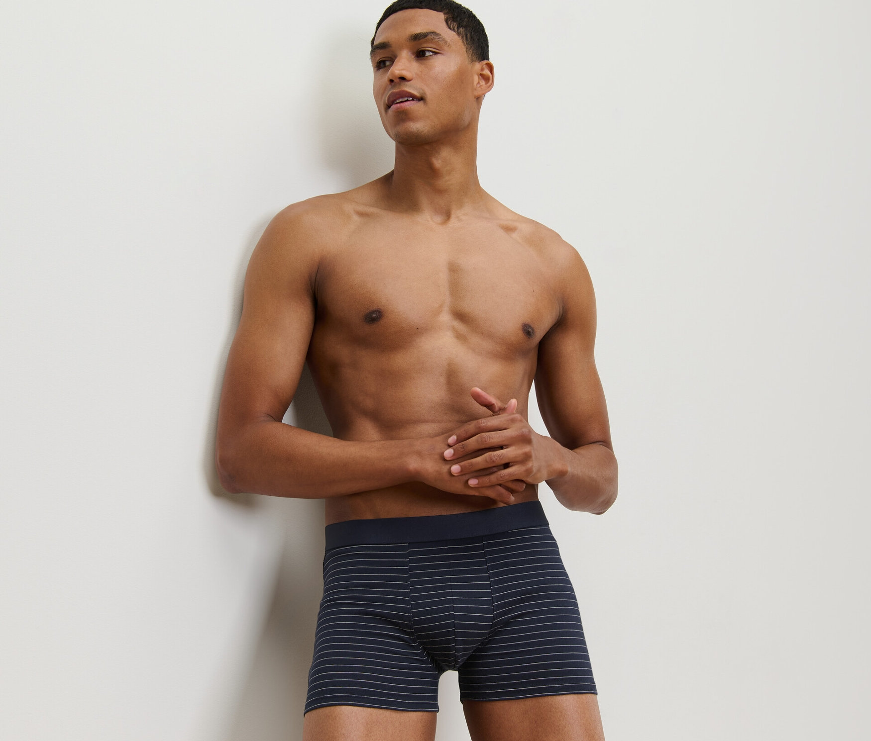 Un homme appuyé contre un mur porte un des 2 boxers.