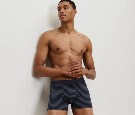 Un homme appuyé contre un mur porte un des 2 boxers.