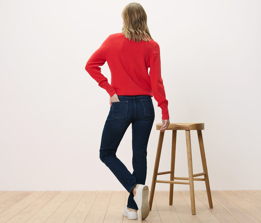 Une femme, vue de dos, porte un jean slim – Fit « Emma » et un pull rouge.