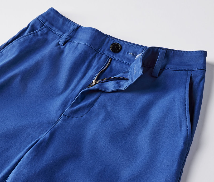 Gros plan sur un pantalon chino bleu cobalt avec une fermeture éclair ouverte.