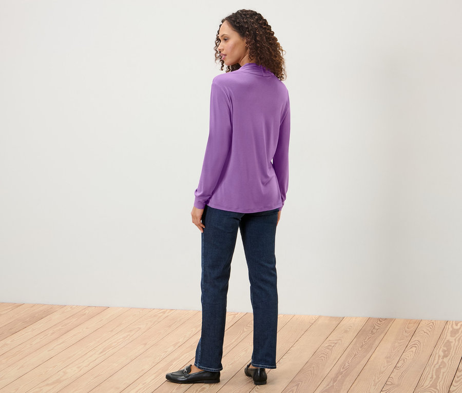 Femme regardant par-dessus son épaule et portant une blouse avec encolure en V, un jean et des mocassins.