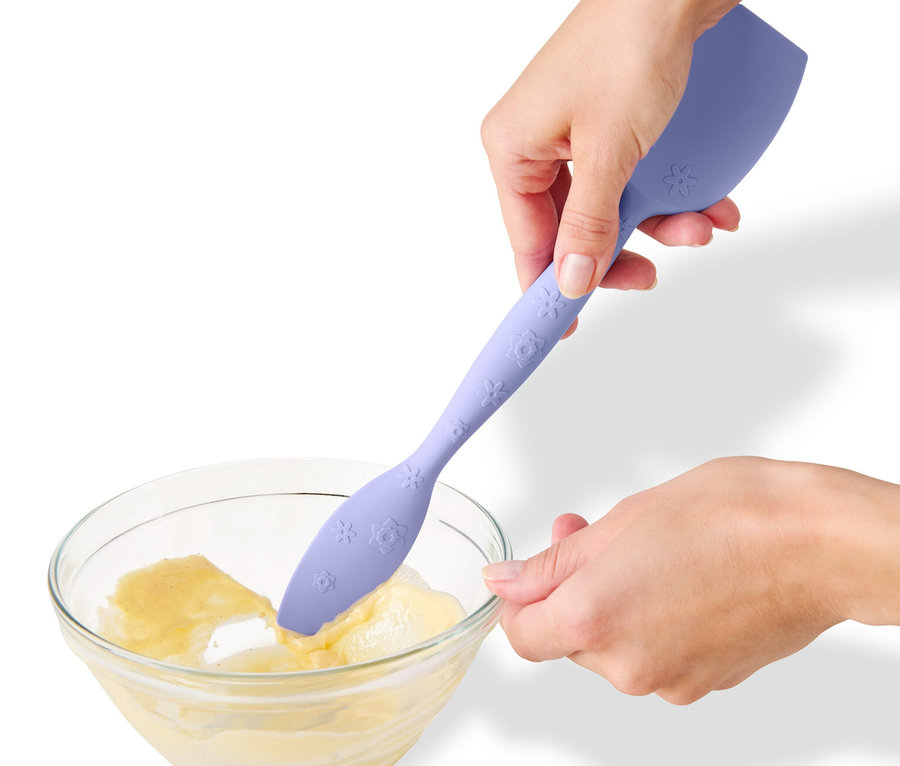 Une personne mélange de la pâte dans un bol avec une cuillère à pâte multifonctions.