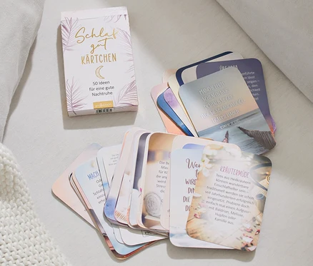 Sur un lit, un paquet et des cartes de l'ensemble de cartes pour s'endormir sont étalés.