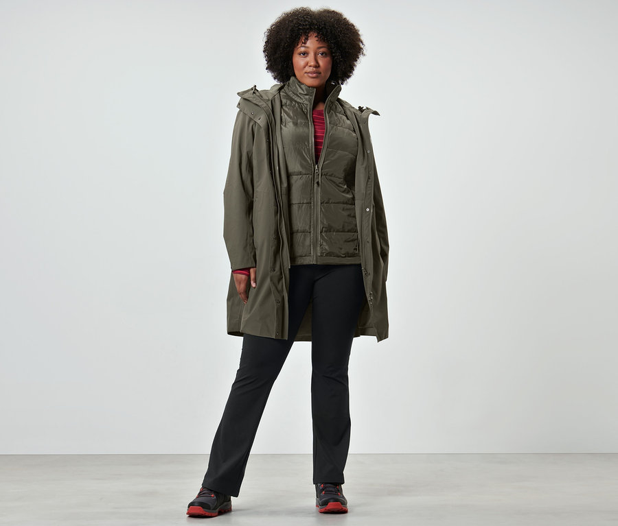 Une femme porte un manteau de pluie 3-en-1 avec gilet, un t-shirt de sport manches longues et un pantalon jazz thermique.