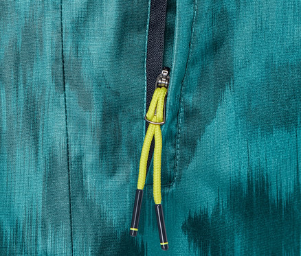 Gros plan sur un pantalon de pluie avec imprimé intégral et fermeture éclair partiellement ouverte.