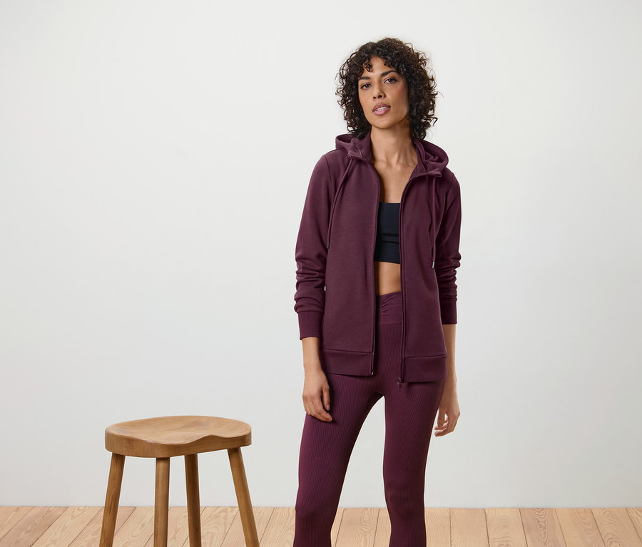 Femme portant une jaquette en sweat, des leggings et un débardeur de sport.