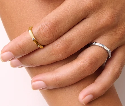 Gros plan d'une main de femme portant une bague Octogone en argent 925 dorée et une bague Octogone en argent 925.