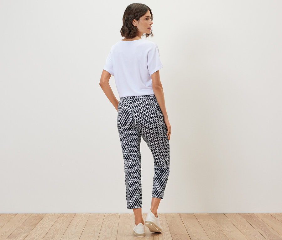 Femme vue de dos portant un t-shirt blanc et un pantalon en jersey imprimé.